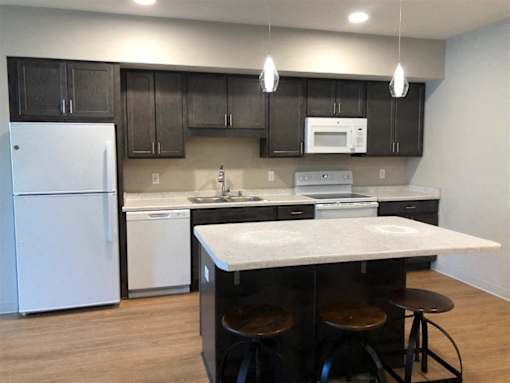 A kitchen with a white fridge and black cabinets.
