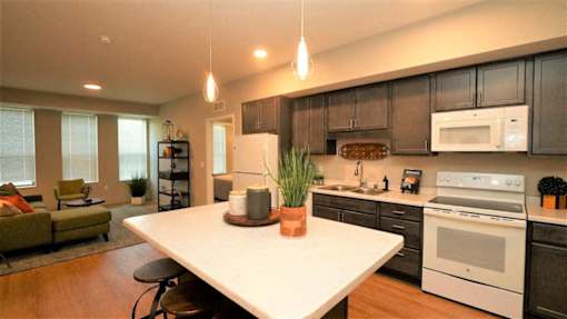Modern kitchen island and open living area at Morrow Apartments in St. Paul, MN, featuring dark cabinetry