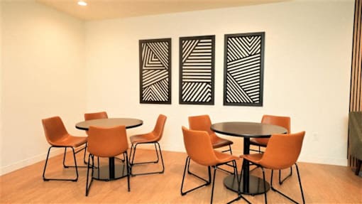A room with a table and chairs and three paintings on the wall.