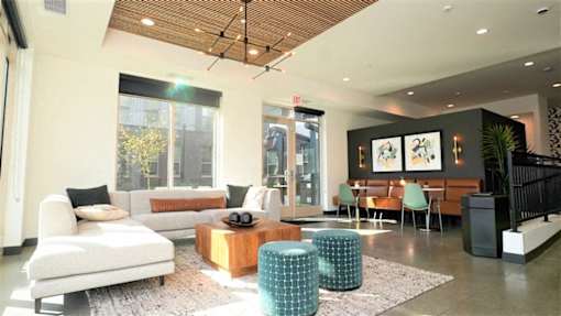 A modern living room with a white sofa, a wooden coffee table, and a green ottoman.
