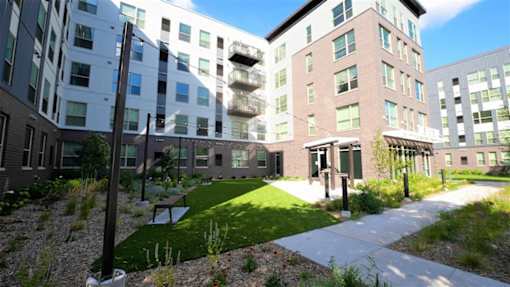 A modern building complex with a grassy area in front.