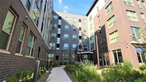A modern building with a walkway between it and a grassy area.