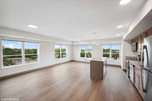A kitchen with a refrigerator, sink, and wooden floors.