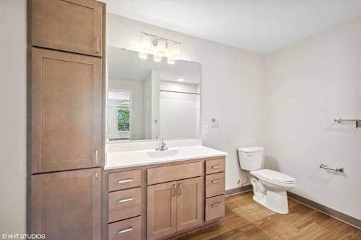 A bathroom with a toilet, sink, and mirror.