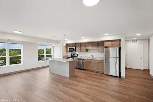 A modern kitchen with wooden floors and stainless steel appliances.