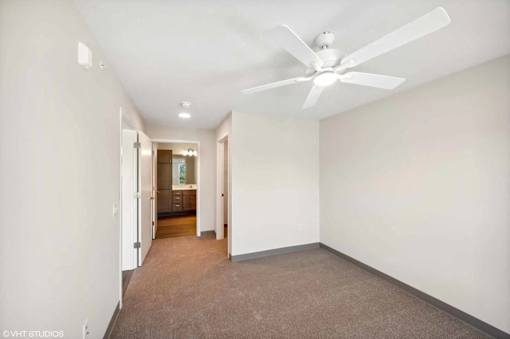 A room with a ceiling fan and carpeted floor.