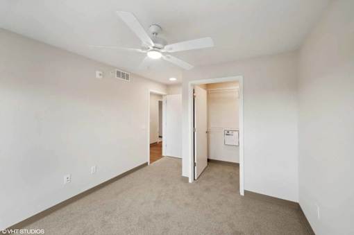 A room with a ceiling fan and carpeted floor.