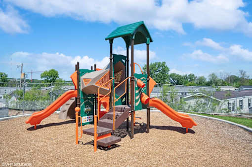 A playground with a green roof and orange slides.