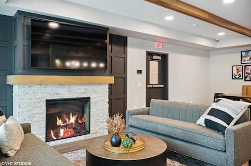 A cozy living room with a fireplace and a grey couch.