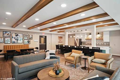 A modern living room with a grey sofa, wooden coffee table, and a dining area in the background.