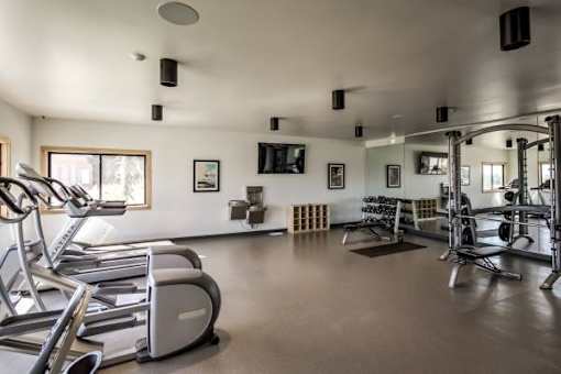 A spacious gym with treadmills, elliptical machines, and weightlifting equipment.