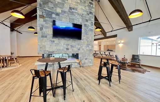 A modern living room with a stone fireplace and wooden floors at Silverbrook Apartments Apartments, Ridgeland, MT, 59901
