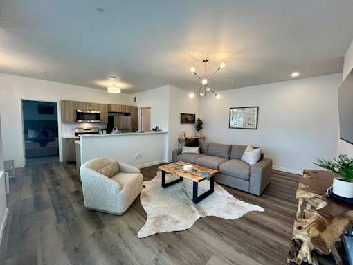 A modern living room with a grey sofa, a white armchair, and a wooden coffee table at Silverbrook Apartments Apartments, Kalispell