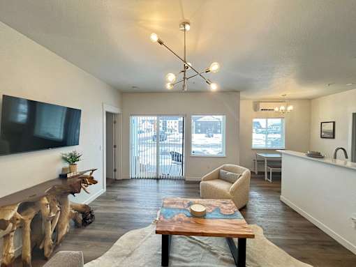A living room with a wooden table and a television on the wall at Silverbrook Apartments Apartments, Ridgeland, MT, 59901