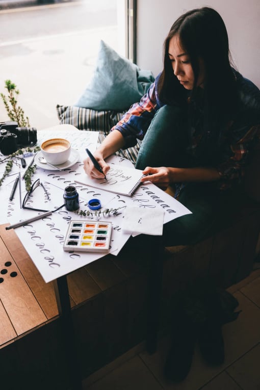 a woman sitting at a table drawing on a piece of paper at Copestone, Idaho, 83714