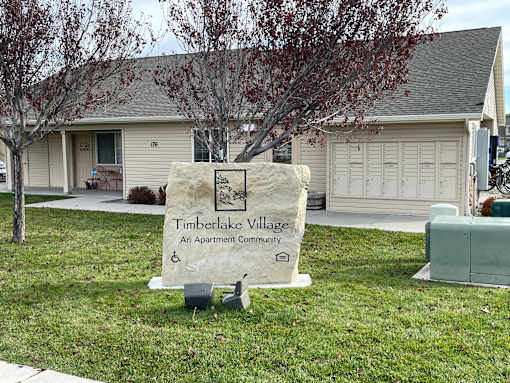 A sign for Timberlake Village Apartment Community stands in the grass.