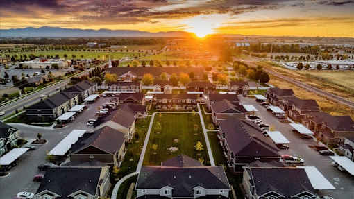 A sunset view of a residential neighborhood with houses and parked cars.