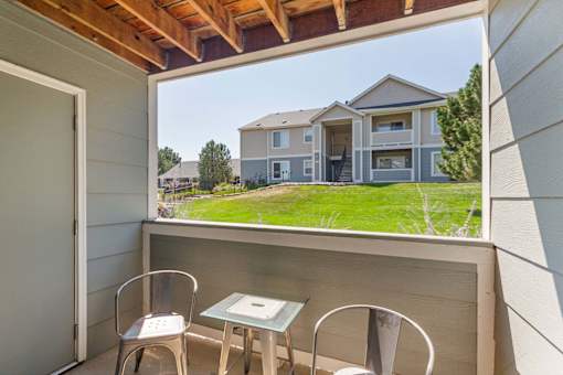 A patio with a table and chairs overlooks a house.