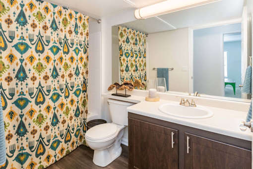 A bathroom with a toilet, sink, and shower curtain.