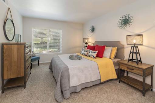 A bedroom with a bed, nightstand, and a wooden cabinet.
