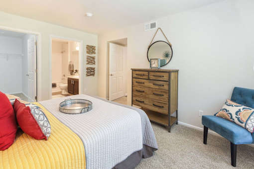 A bedroom with a bed, dresser, and chair.