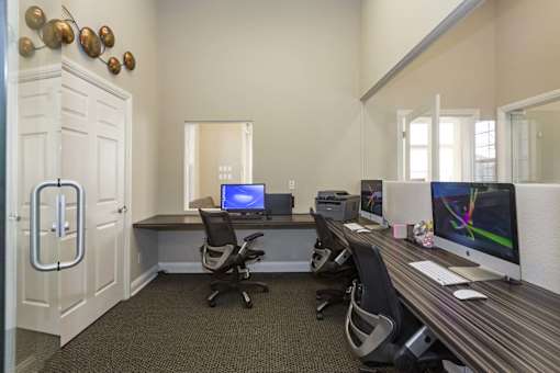 A room with a desk, chairs, and a computer monitor.