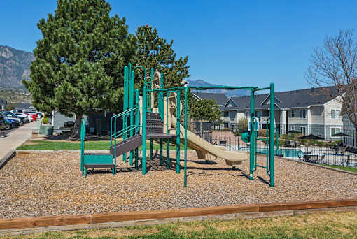 A playground with a green swing set and a yellow slide.