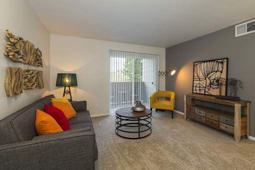 A living room with a grey couch, a yellow chair, and a wooden side table.