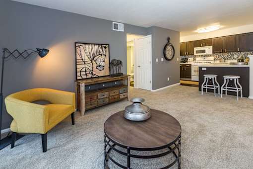 A yellow chair sits in a living room with a coffee table in front of it.