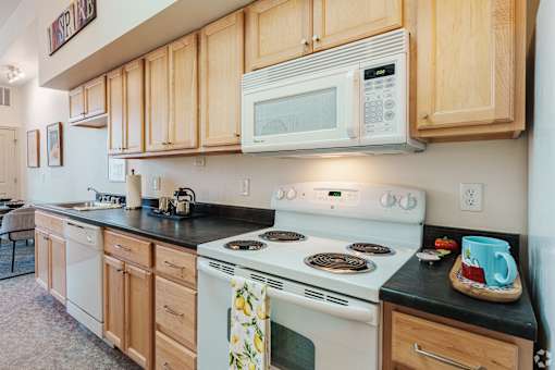 A kitchen with a white stove and wooden cabinets.