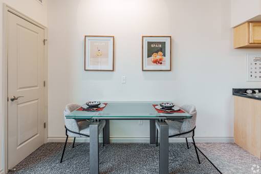 A dining room with a glass table and two chairs.