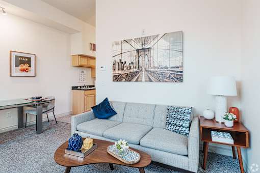 A living room with a grey couch, a coffee table, and a large picture of a bridge hanging on the wall.