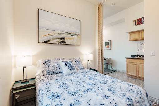 A bedroom with a large bed and a painting on the wall.