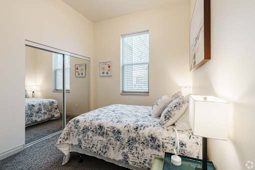 A bedroom with a bed and a mirror.