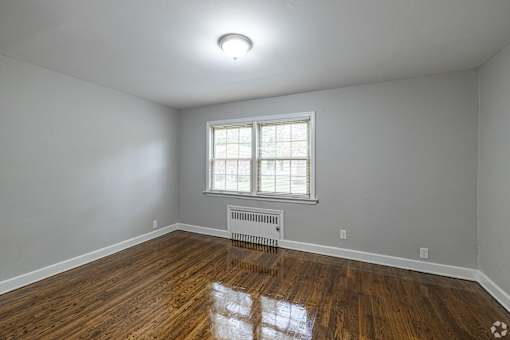 A room with a window and a radiator on the floor.