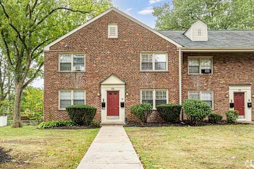 A brick house with a red door and a white door.