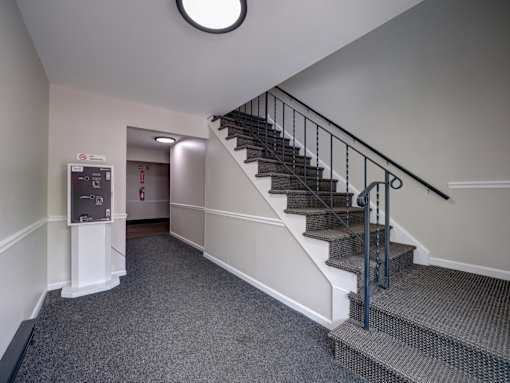 A staircase with a metal railing and a round light fixture on the ceiling.