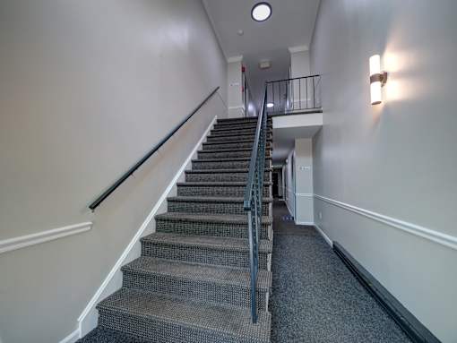 A staircase with a metal railing and a carpeted floor.