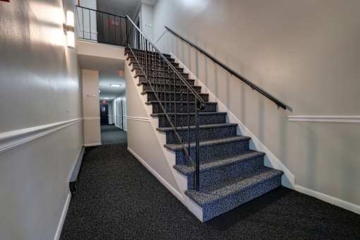 A staircase with a metal railing and a carpeted floor.
