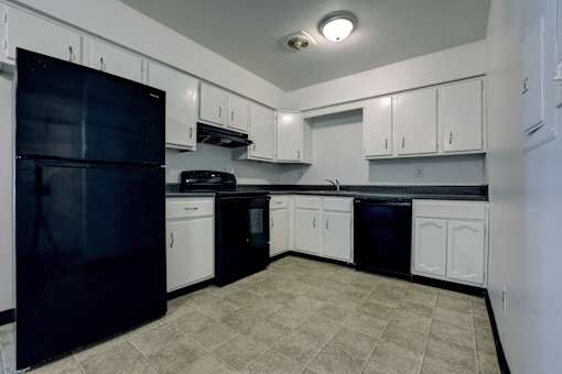 A kitchen with black appliances and white cabinets.