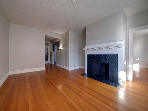 A room with a fireplace and wood flooring.