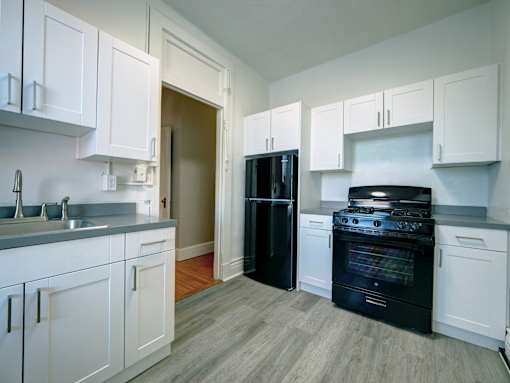 A kitchen with black appliances and white cabinets.