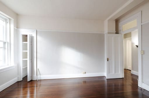 an empty room with a hard wood floor and white walls
