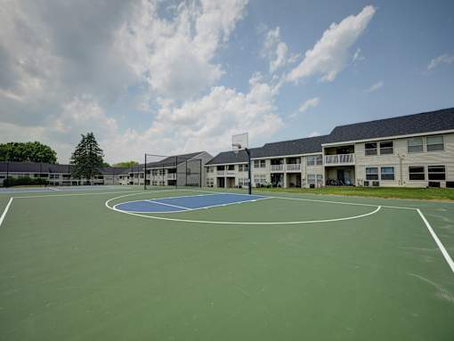A basketball court is surrounded by apartment buildings.