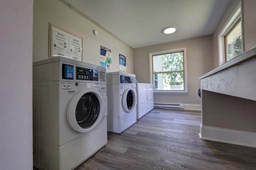 A laundry room with two washing machines and a window.