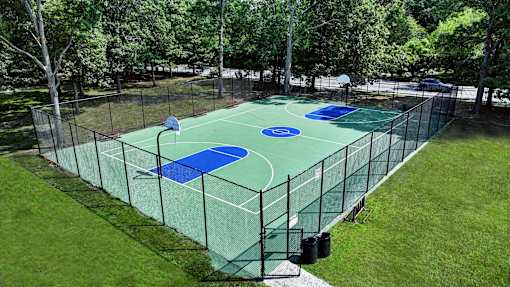 A basketball court surrounded by a fence and trees.