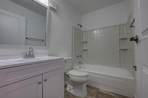 A white bathroom with a toilet, sink, and bathtub.