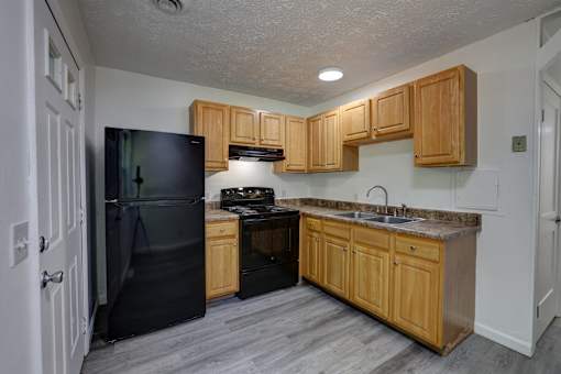 A kitchen with wooden cabinets and a black refrigerator.