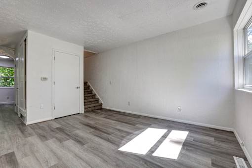 A room with a white door and a staircase leading to another room.