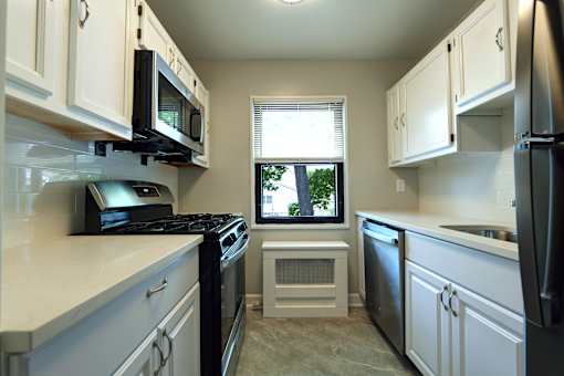 A kitchen with black appliances and white cabinets.